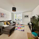 Modern living room with sofa and colourful rug.