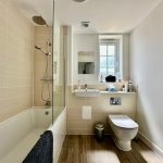 Modern bathroom with shower, toilet, and sink.