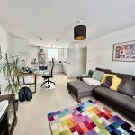 Modern living room with colourful carpet and sofa.