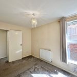Empty carpeted room with window and chandelier light.