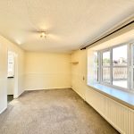 Bright living room with large window and carpeted floor.
