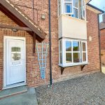 Brick house entrance with white door and window.