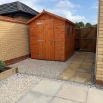 Garden shed on gravel in fenced backyard