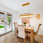 Modern dining room with table, chairs, chandelier, garden view.