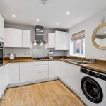 Modern white kitchen with wooden surfaces.