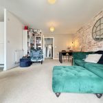 Modern living room with green sofa and brick wall.