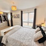 Modern bedroom with open wardrobe and large window.