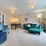 Cosy living room with green sofa and armchair.