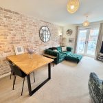 Modern living room with green sofa and brick wall.