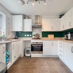 Modern kitchen with white cabinets and appliances.