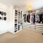Organised wardrobe with shoes, clothes, and hats displayed.