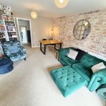 Cosy living room with green sofa and bookcase.