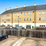 Modern townhouse exterior with parking and garden view.