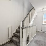 Modern grey-carpeted staircase with white rails