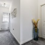 Carpeted corridor with vase and picture frames.