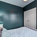 Small bedroom with teal walls and white bedding.