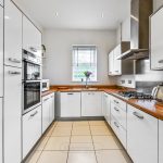 Modern white kitchen with wooden countertops and appliances.