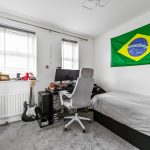 Bedroom with Brazilian flag, desk, and guitar.
