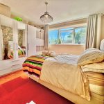 Cosy bedroom with colourful blanket and white furniture.
