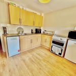 Modern kitchen with light wood cabinets and appliances.