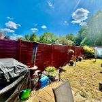 Sunny garden with fence and plants.