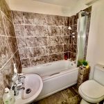 Modern bathroom with grey tiled walls and white fixtures.