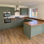 Modern kitchen with green cabinets and wooden worktops.
