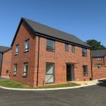 Modern red brick house under clear blue sky.