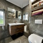 Modern bathroom with sink, mirror, and window view.