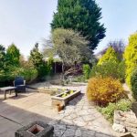 Garden patio with chairs and lush greenery.