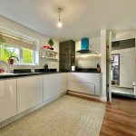 Modern kitchen with white cabinets and green plants.