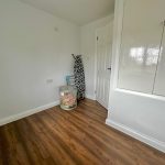 Bright room with wooden floor and ironing board.