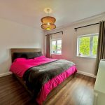 Modern bedroom with wooden floor and large windows.