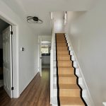 Bright hallway with wooden floors and carpeted stairs.