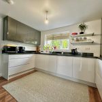 Modern kitchen with sleek cabinets and wooden floor.