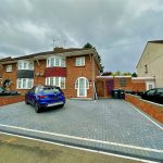 Brick house with driveway and parked cars.