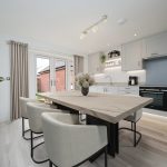 Modern kitchen with marble island and stylish chairs.