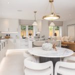 Modern white kitchen with dining area and decor.