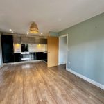 Modern kitchen with wooden floor and pendant light.