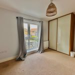 Bright room with curtains and wardrobe, neutral colours.