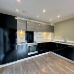 Modern kitchen with black cabinets and wood flooring.