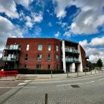 Modern red brick building with balconies and sky.