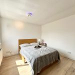 Bright bedroom with double bed and window view.