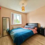 Cosy bedroom with bed, mirror, wardrobe and soft lighting.