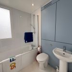 Modern bathroom with blue cabinets and white fixtures.