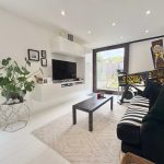 Modern living room with pinball machine and plants.