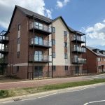 Modern brick apartment building with balconies and blue sky.