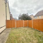 Fenced garden outside house with cloudy sky