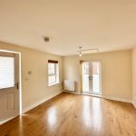 Bright, unfurnished living room with wooden flooring.