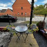 Small patio with glass table, plants, and black car.